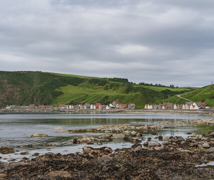 Crovie Fishing Village nestled along the Aberdeenshire coast with green hills and a rocky shore