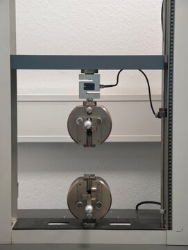 Universal testing machine tensile grips and crosshead in laboratory frame for material testing