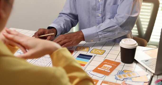 Creative team collaborating on UX and UI design using wireframes, interface components, color palettes, and planning materials to develop digital products through design thinking and teamwork.