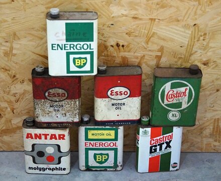 Vintage motor oil cans stacked against wooden background