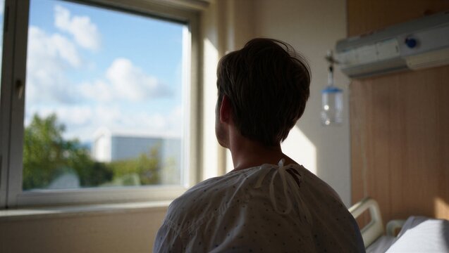A patient in a hospital gown gazes out the window, contemplating life. The scene conveys a sense of hope and reflection.
