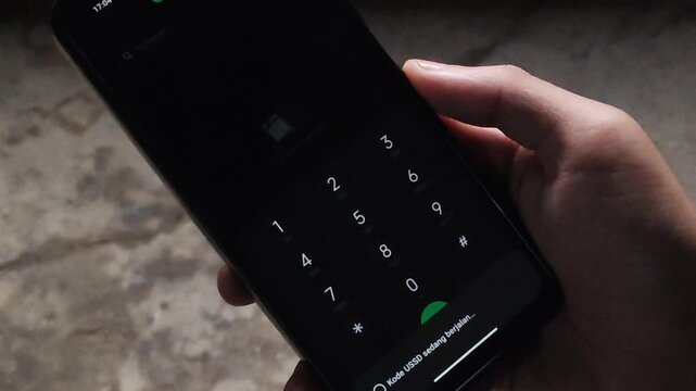Close Up of Hand Holding Smartphone Running USSD Code Dial MMI Code on Screen