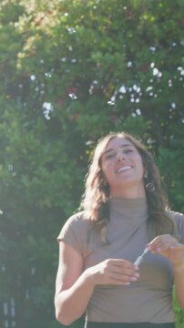 Vertical video: Smiling couple celebrating in yard, woman dipping wand and blowing bubbles, ring