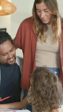 Vertical video: Turning child leading mom rust top leaning at home seeing art, dad pointing pencil