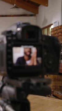 Vertical video: Recording DSLR cam on tripod showing man gesturing and emphasizing in studio on LCD