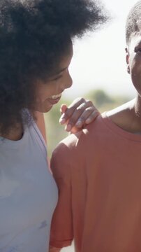 Vertical video: Placing hand, couple leaning and hugging at park showing love in blue and rust tops