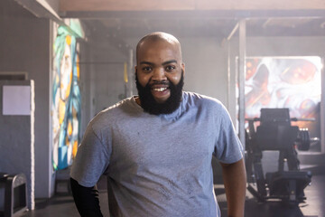 Male standing and posing at gym near weight machine and bench, with mural panels © wavebreak3