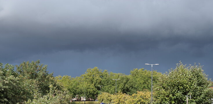 Dark menacing arcus storm cloud passing by from left over the tree horizon
