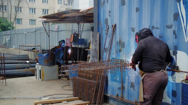 Construction workers welding rebar at outdoor job site