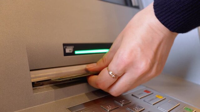 Close-up view of female hands taking one hundred dollar bills from an atm cash dispenser, illustrating a financial transaction and money withdrawal at an automated banking terminal