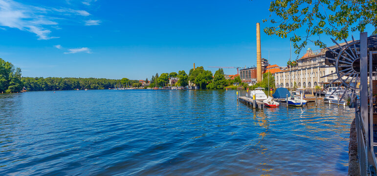 Berlin im Hochsommer: Blick vom Ufer am M&uuml;ggelpark auf die denkmalgesch&uuml;tzten Geb&auml;ude der alten Berliner Brauerei und M&uuml;ggelspree inkl. Marina und Boote am Ufer in Friedrichshagen, Sommerzeit & Ferien
