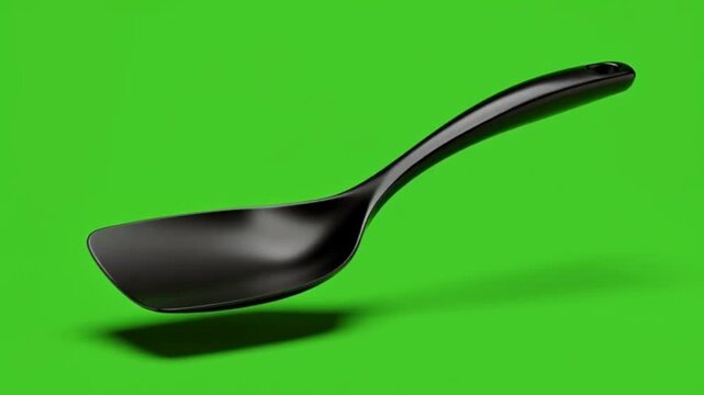 Black Plastic Spoon Floating Against Bright Green Background