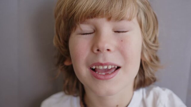 Six year old boy excitedly checks his loose upper incisor baby teeth with his finger, revealing the early stages of a supernumerary tooth
