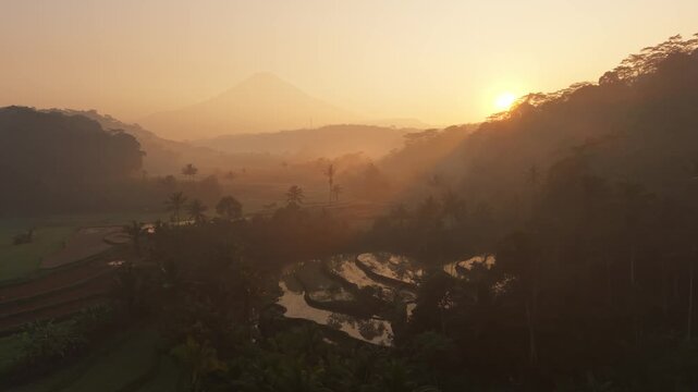 Aerial view of a misty sunrise over the river and rice fields in Selomerto, Central Java, Indonesia.