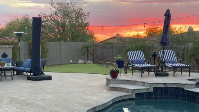 A 4k video clip of a travertine tiled pool deck in Arizona featuring an outdoor fire place, pool, spa and putting green.