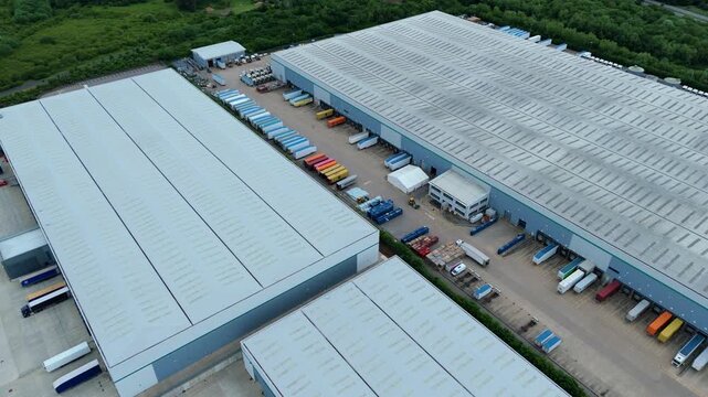 Aerial view of commercial warehouses with loading docks and parked semi-trucks in an industrial park in Kettering, England, United Kingdom.