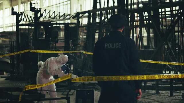 Police officer guarding crime scene while forensic experts document evidence