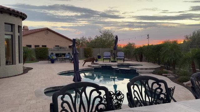 A 4k video clip of a travertine tiled pool deck in Arizona featuring an outdoor fire place, pool, spa and putting green.