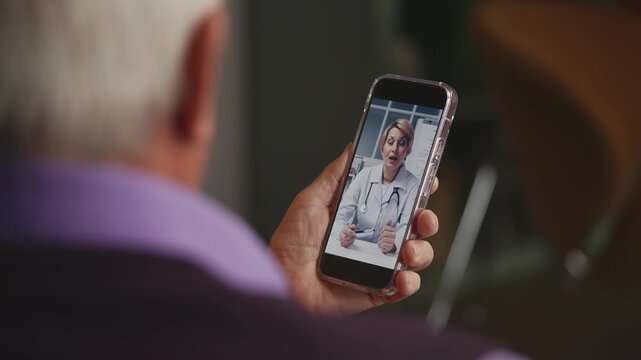 Senior man consulting with female doctor via video call on phone, telemedicine