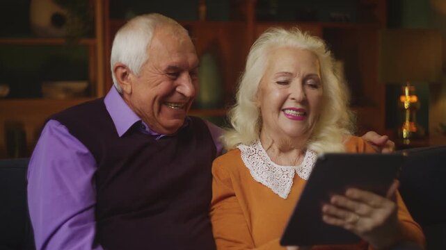 Elderly woman and her husband talking to their children via video call on tablet