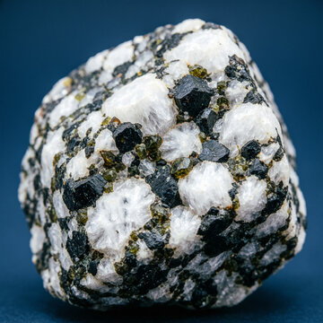 Gabbro igneous rock macro with coarse mineral crystals on dark slate blue background