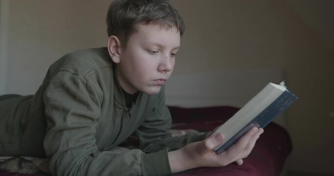 Caucasian Boy Kid Read Bible Book Lying on Bed in Bedroom. 4K 10-bit