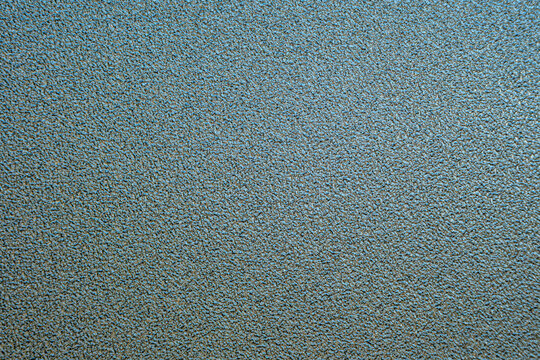 Close-up of a blue gray teal grainy textured surface. Abstract textured background with fine rough details, metallic or slate effect.