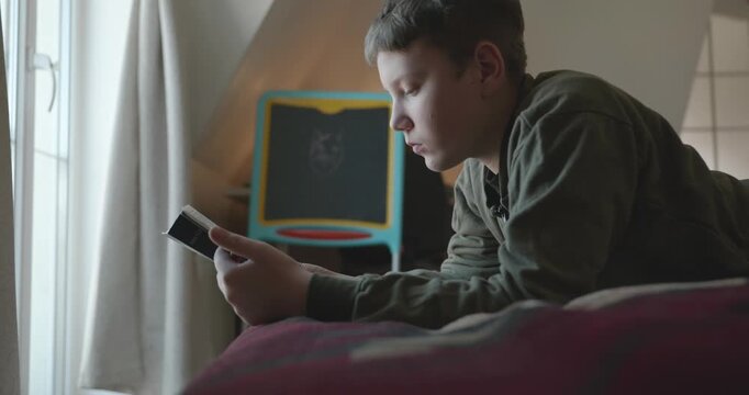 Caucasian Boy Kid Read Bible Book Lying on Bed in Bedroom. 4K 10-bit