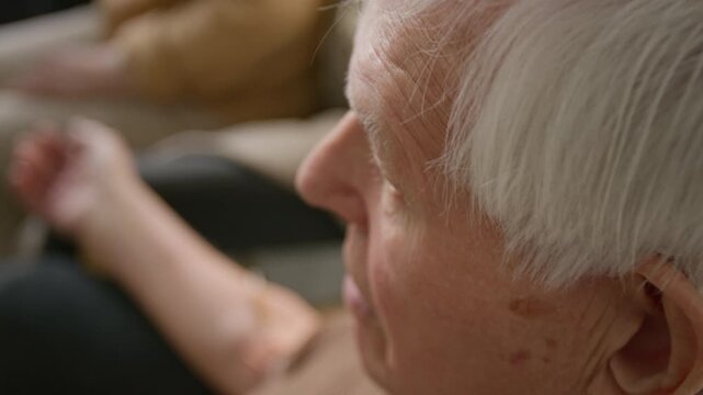 Side view close up shot of senior man talking while getting IV drip in retirement home. Footage for senior care and wellness programs