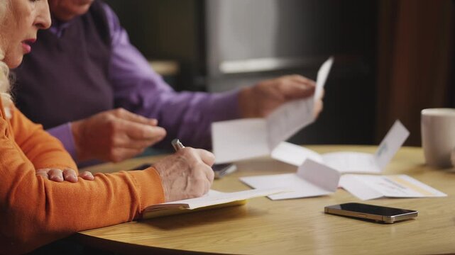 Couple in their 70s calculating expenses while checking overdue bills, budget