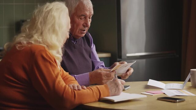 Senior man and his wife reading overdue bills and calculating household expenses