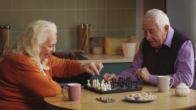 Positive elderly couple playing chess and high-fiving after a winning move