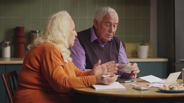 Senior woman and her husband opening envelope, upset about overdue bills