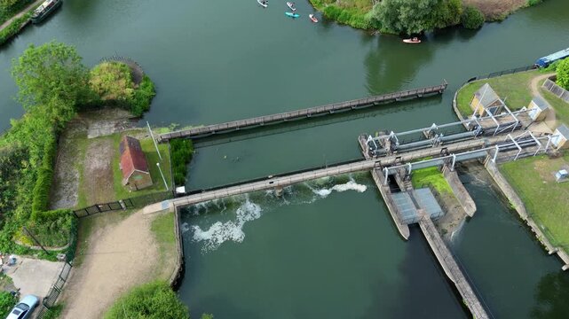 Aerial view of Feildes Weir Lock on the River Lee with flowing water, green banks, and small boats in Hoddesdon, England, United Kingdom.
