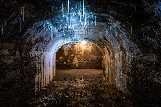 Historic bunker tunnel from world war 2 built with reinforced concrete now is a scary lost place in the dark with stalactites, old light bulbs, wet walls, spooky atmosphere.