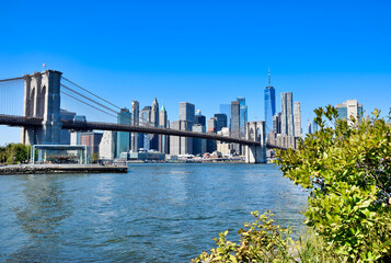 Obraz premium Brooklyn Bridge granite tower and sweeping span close-up from East River with One World Trade Center behind, New York City, USA