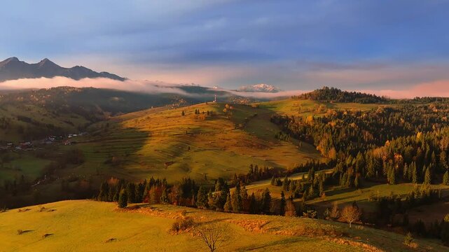 Osturna, Slovakia - 4K Flying by the High Tatras Mountains near the village of Osturna on a sunny, foggy autumn day at sunrise. Warm colors, autumn foliage, blue sky