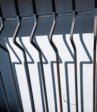 Abstract graphic shadow of metal security bars and window shutters on a wall