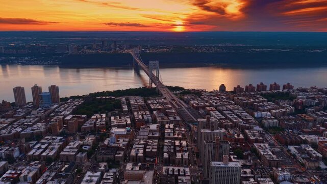Moving over the residential area at the Hudson River waterfront. Setting sun colors the cloudy sky orange.