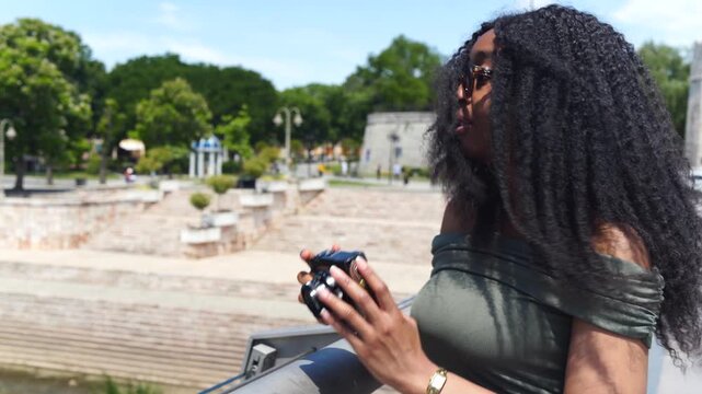 Young black woman traveler taking a photo with a camera on the street on a sunny day in Europe, Nis, Serbia