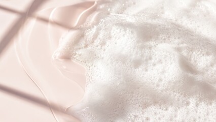 Fototapeta premium Close-up of white foam bubbles with soft light and subtle pink background texture