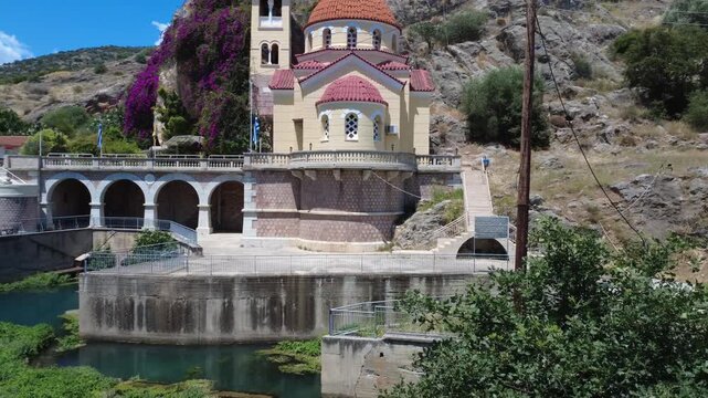 Low aerial view of Orthodox church beside stone bridge and spring