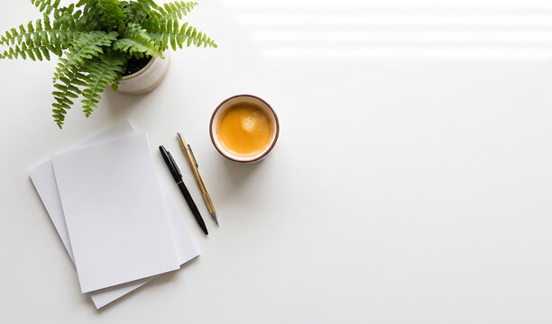 Overhead view of office desk with plant, coffee, notepad and pens