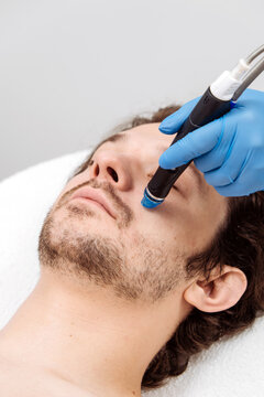 Professional facial skincare procedure with HydraFacial device for male client. Concept skin cleansing, hydration and aesthetic medicine.
