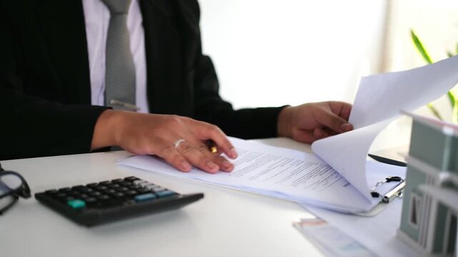 Businessman checking, filing work documents, organizing paperwork, reading contracts and accounting documents. Busy work at office desk.