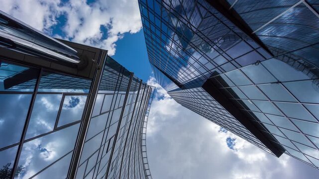 Downtown skyscrapers time-lapse from street level, low angle view of glass high-rise office buildings, financial district, sunny blue sky with clouds