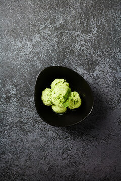Minimalist flat lay of matcha green tea ice cream in a black bowl