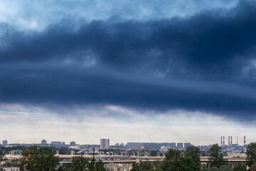 Obraz premium Thick smoke floating over city area, fire accident at automobile tire production plant facilities, danger of modern factories placed next to residential areas, industrial development and urbanization.