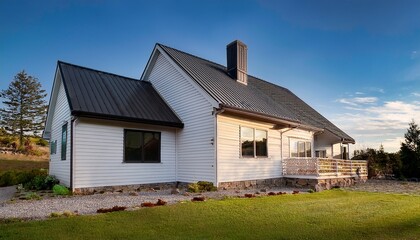 Fototapeta premium modern white farmhouse with dark metal roof stone chimney and covered porch side perspective
