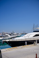 Fototapeta premium Luxury yachts and motorboats moored at the pier in Alanya marina. Mediterranean sea resort, nautical transportation, summer vacation travel and coastal tourism business concept in Turkey, investment